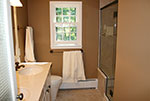 A white bathroom vanity with a marble vanity top and custom shower
