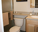 A bathroom with a maple shaker door vanity, toilet and a banjo vanity top.