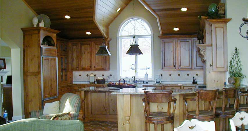 A Rustic cherry wood-mode Kitchen with an island and wood paneled sub-zero refrigerator.