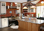 A kitchen with white perimeter cabinets and an oak island.