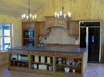 A rustic knotty pine kitchen with a wood mantel hood.