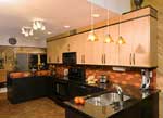 A contemporary kitchen with black lower cabinets and maple upper cabinets.