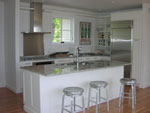 A contemporary white flat panel kitchen with stainless steal knobs.