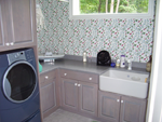 A laundry room with a apron sink and custom cabinetry 