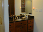 A bathroom with a cherry vanity and a black vanity top.